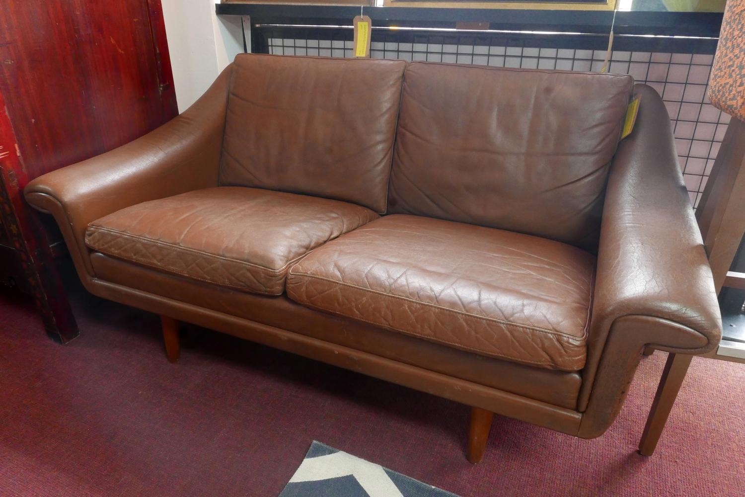 A 20th century Danish tan leather sofa raised on teak legs