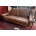 A 20th century Danish tan leather sofa raised on teak legs