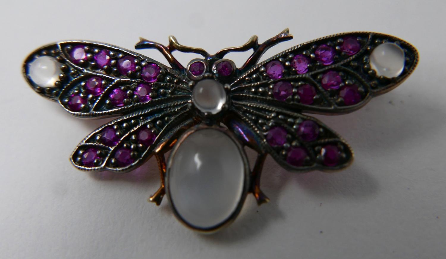 A yellow gold butterfly brooch studded with rubies and four moonstone cabochons, 1.5 x 3.5cm, 3.4g