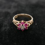 A boxed 9ct yellow gold diamond and ruby flower-cluster ring to pierced heart-shaped shoulders,