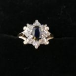 A boxed, 9ct yellow gold sapphire and diamond cluster ring with scrolling shoulder detailing,