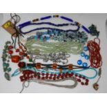 A large collection of semi-precious hardstone beaded necklaces to include coral, cinnabar lacquer,