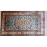 A Turkish silk Kayseri rug with floral medallion, on a blue and beige ground, contained by floral