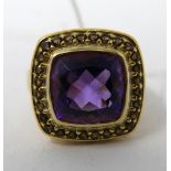 A silver-gilt natural amethyst ring, centrally set with a large cushion-cut amethyst framed by an