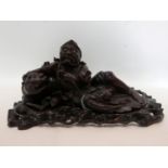 A late 19th/early 20th century Chinese hardwood carving of a man laying with his dog, raised on