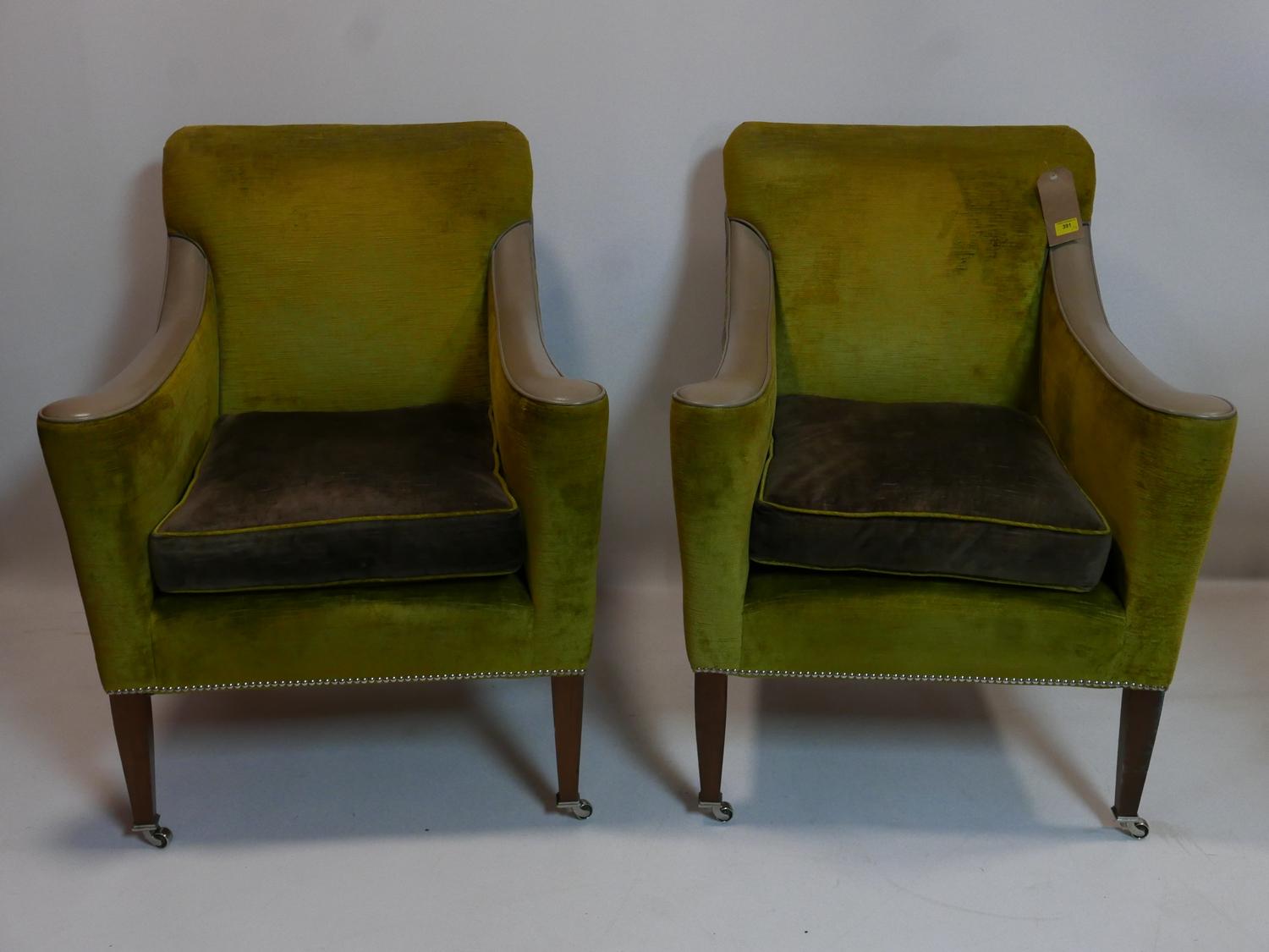 A pair of contemporary armchairs with green and grey velour upholstery and leather arm rests, raised