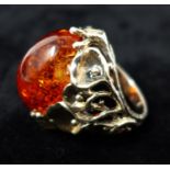 A sterling silver and amber cabochon ring set within an organic floral mount