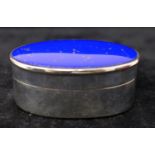 A sterling silver oval-shaped pill box inset with a polished lapis lazuli cabochon to the lid