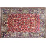 A Persian rug with floral motifs and spandrels, on a red ground, contained by floral border, 200 x