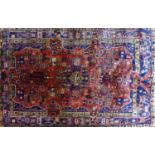 A North West Persian Nahawand rug, central floral medallion with repeating petal motifs on a rouge