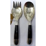 A white metal serving spoon and fork, with pierced and engraved floral decoration and ebony handles,