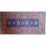 A Persian rug with geometric design on a blue, red and beige ground, 142 x 72cm