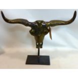 A bronzed bull skull, on a stand, H.57 W.57cm