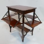 An Art Nouveau mahogany lamp table with folding shelves and walnut cross banding