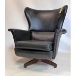 A 20th century wing back swivel chair in black vinyl