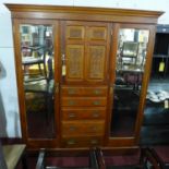 An Art Nouveau walnut wardrobe with central carved door, above five graduating drawers, flanked by