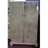 A 20th century floral leather clad wardrobe, raised on bun feet, H.140 W.90 D.56cm