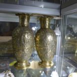 A pair of Middle Eastern brass vases, with repousse embossed decoration of figures and animals in