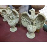 Two reconstituted stone eagles seated atop balls, raised on socle bases, H.70 W.49cm (2)