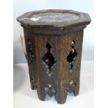 An early 20th century Nomad's table, the octagonal top with carved geometric decoration above