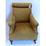 A Victorian velour upholstered armchair raised on turned legs and castors