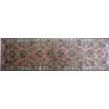 A North West Persian Sarouk runner, repeating stylised floral motifs on a pink ground, within