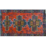 A Persian rug with three geometric medallions, on a red & blue ground, contained by geometric