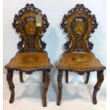 A pair of late 19th century carved black forest hall chairs with marquetry inlay, both have had