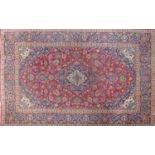 A Kashan carpet with central floral medallion, on a red & blue ground, contained by floral