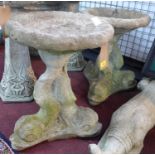 Two reconstituted stone aged bird baths, raised on triple dolphin supports, H.49cm