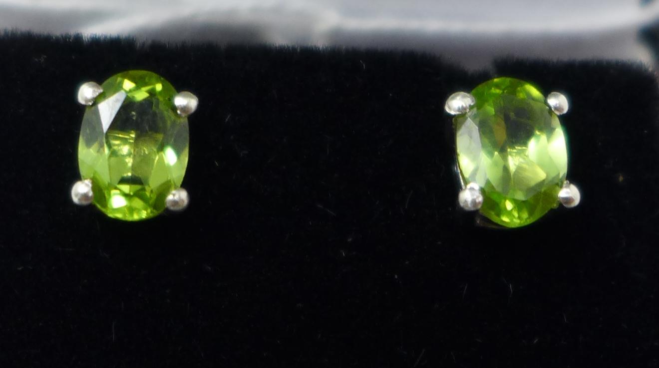 A boxed pair of sterling silver and faceted, oval peridot stud earrings, g.