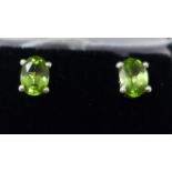 A boxed pair of sterling silver and faceted, oval peridot stud earrings, g.
