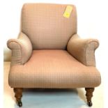 A Victorian upholstered armchair raised on turned legs and castors