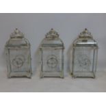 A set of three contemporary storm lanterns, distressed painted and with floral decoration, raised on
