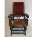 An ebonised rocking chair, with velour seat, backrest and armrest, on turned supports and castors,