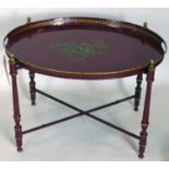A 20th century Italian red toleware tray, with gilt floral decoration, raised on folding stand