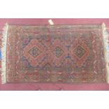 An antique Afghanistani Beluchi hand-made woolen rug, three diamond medallions on a dark blue