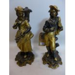 A pair of gilt resin figures of a Shepherd and Shepherdess standing by a tree stump, raised on C-