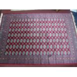 A Bokhara style carpet with repeating elephant pad motifs, on a red ground, contained by geometric