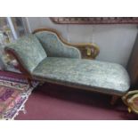 A Victorian mahogany chaise longue with floral velour upholstery, raised on turned legs and castors