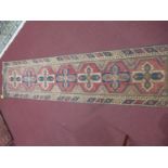 A 20th century Turkish runner with geometric design, on a red ground, 276 x 66cm