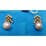A boxed pair of 18ct yellow gold earrings, with diamond-studded bow tops each suspended by a pear-