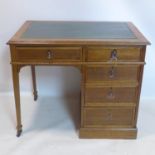 An Arts and Crafts oak kneehole desk, with green leather skiver, having an arrangement of five