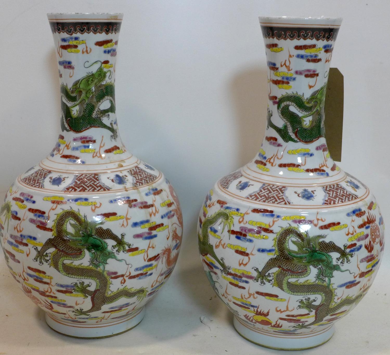 A pair of Chinese, Republic period famille rose bottle vases decorated with dragons chasing the