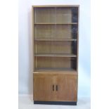 An early 20th century oak bookcase, with sliding glass doors revealing shelves above two cupboard