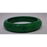 A Chinese, spinach green jade bangle hand-carved with floral tendrils, dia: 6cm, 48g