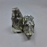 A pair of silver plated condiments in the form of textured boars heads each with faceted ruby