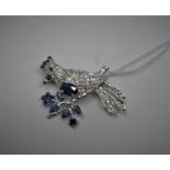 A sterling silver brooch in the form of a bird on branch studded with white sapphires, blue