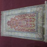 An antique silk Turkish Hereke carpet with tree of life design, on a red and beige ground, contained
