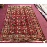 A North East Persian Turkoman rug, repeating stylised goul motifs on a rouge field, complimented